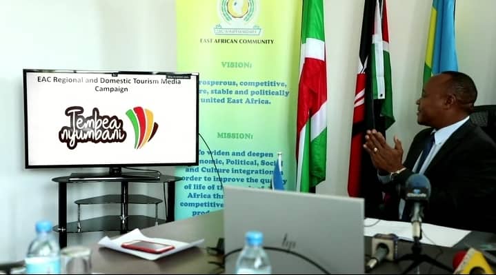EAC Secretary General Dr. Peter Mathuki claps as he looks at the official logo of the media campaign