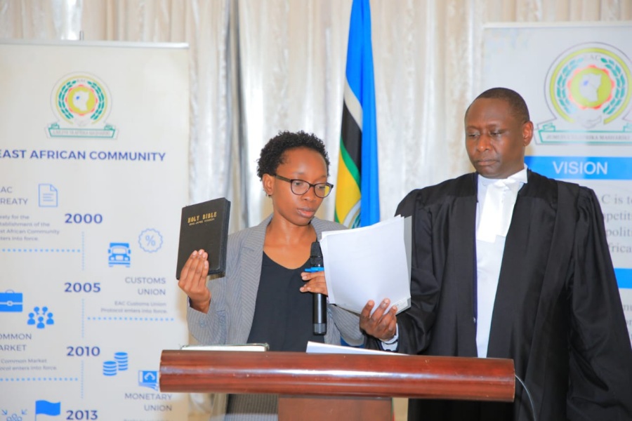 Ms. Dorcas Siloya, an accountant at the Lake Victoria Basin Commission in Kisumu, Kenya, takes the oath of allegiance in Arusha. Administering the oath is the Counsel to the Community, Dr. Anthony Kafumbe.
