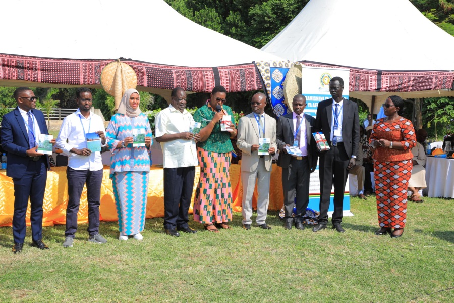Regional leaders and representatives from the EAC Partner States pose for a photo with the book unveiled by EAKC containing policy papers presented during previous years' Kiswahili Day celebrations.
