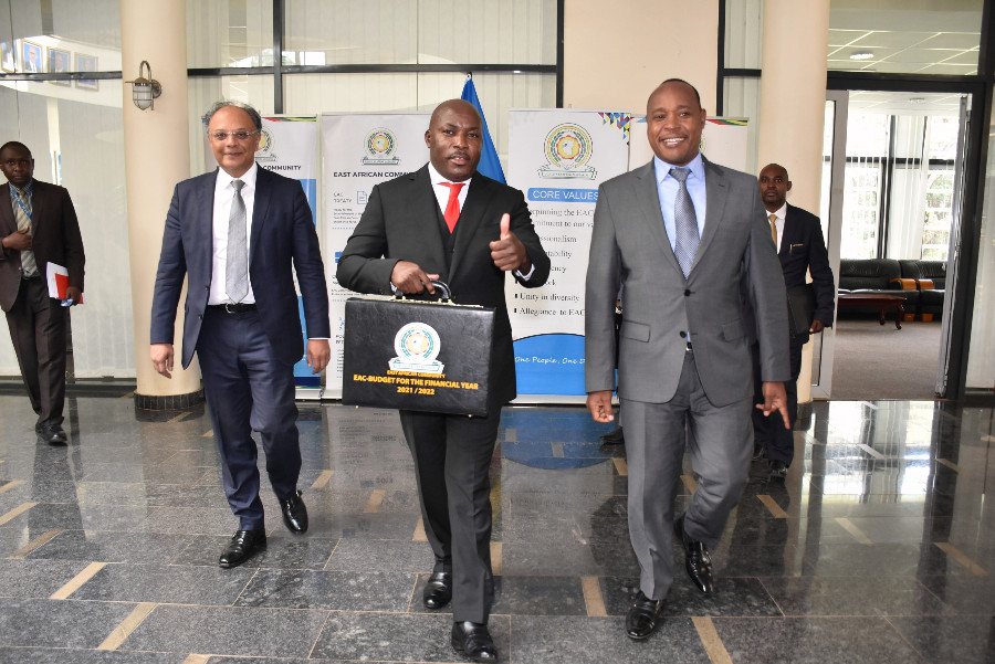  The Chief Administrative Secretary in the Ministry of EAC, Kenya, Hon. Ken Obura, holds the briefcase containing the 2021/2022 budget speech as he heads to the East African Legislative Assembly Chambers in Arusha, Tanzania. With him is EAC Secretary General, Hon. Dr. Peter Mathuki (right), and Dr. Kevit Desai, Kenya's EAC Principal Secretary.