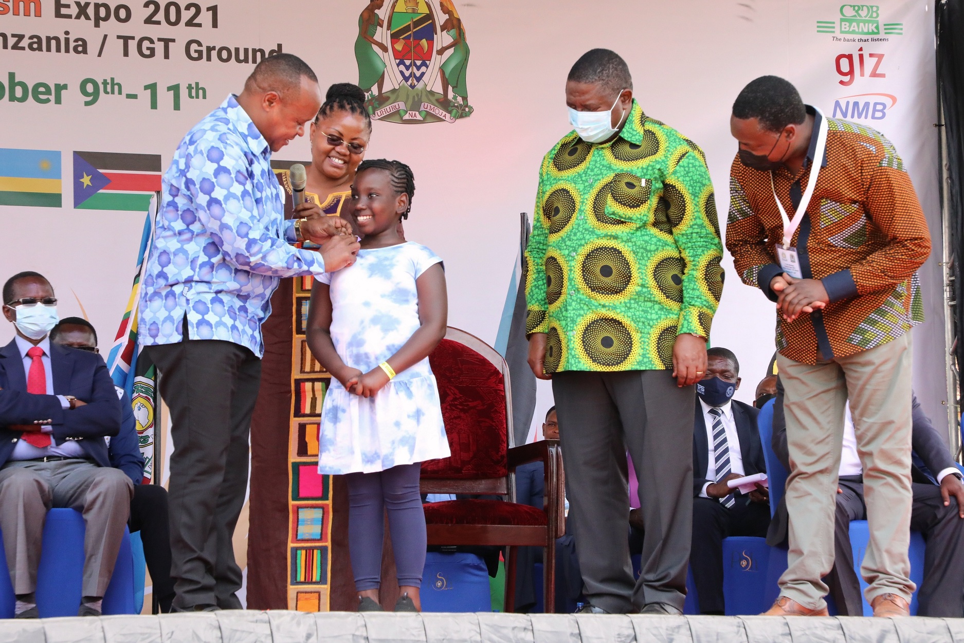 EAC Secretary General Hon. (Dr.) Peter Mathuki (left) confers a badge on Ms. Sharon RIngo designating her as an EAC Ambassador. Ms. Ringo, a standard six pupil, had entertained guests with a poem on EAC integration during the 1st EAC Tourism Expo in Arusha. Looking are the EAC Deputy Secretary General in charge of Planning and Infrastructure, Eng. Steven Mlote, and Mr. Jean Baptiste Havugimana, the Director of Productive Sectors at the Secretariat.