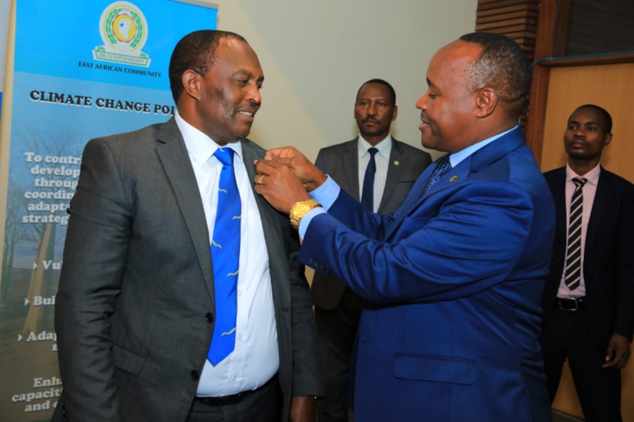 EAC Secretary General Hon. (Dr.) Peter Mathuki gifts a lapel pin to the Chairperson of the Machakos County Kenya Heads of Secondary Schools Association, Mr. Anthony Kitungu, at the EAC Headquarters.