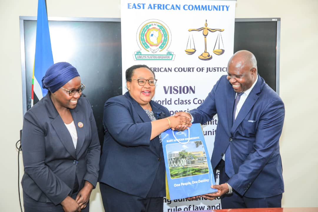 The EAC Judge President, Justice Nestor Kayobera, presents a token of appreciation to the Tanzanian Minister of Constitutional and Legal Affairs, Hon. Amb. Dr. Pindi H. Chana. Looking on is the Permanent Secretary in the Ministry, Ms. Mary Makondo.